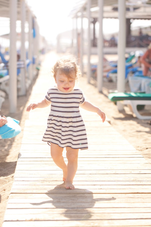 Baby walking along the wooden walkway on the beachの写真素材