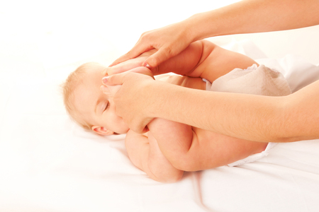Baby massage. Baby feet touching his forehead. Isolated on white backgroundの写真素材