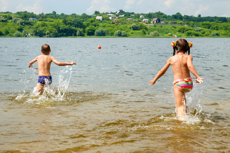 Children running to swim in the river. Summer holidays in the countryside.の写真素材