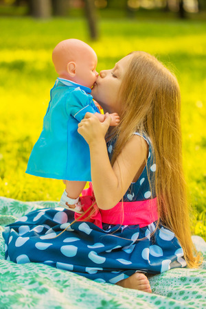 Little girl kissing her doll. Girl playing like a mother and daughterの写真素材