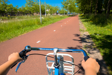 Little child riding a bicycle on bike path. Children's hands hold the handlebar close-up. Eco-friendly transport and healthy lifestyle concept.の写真素材