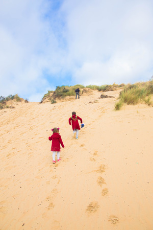 The family, parents and children are climbing the sand dune. Family weekend.の写真素材