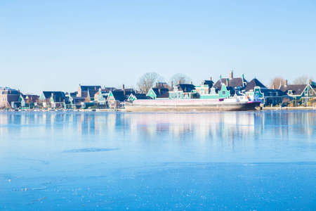 The Netherlands in winter. Winter Dutch village. Vintage beautiful Dutch houses, old windmills, frozen water in canals and rivers.の写真素材