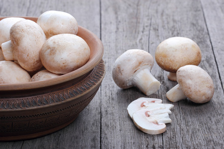 Champignons in a ceramic plate on old wood tableの写真素材