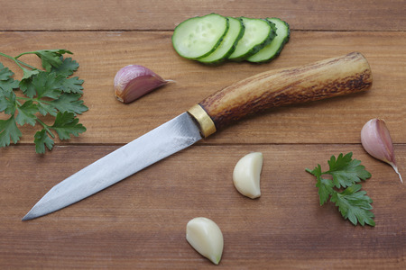 Handmade knife with cucumber, garlic and parsley on wood backgroundの写真素材