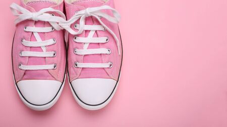 Pair of pink female sneakers on pink background. Closeupの写真素材