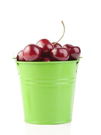 Cherries in green pail isolated on white backgroundの写真素材