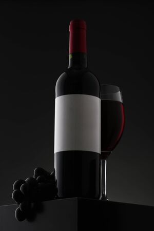 Bottle of red wine with label and wineglass on gradient background. Closeupの写真素材