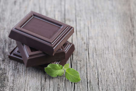 Dark chocolate with leaves on wooden backgroundの写真素材