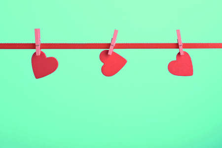 Valentine day greeting card with copy space and hearts pinned to rope on light green backgroundの写真素材