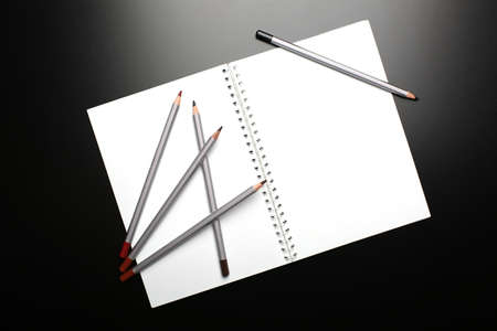Sketchbook with pencils on black background. Top viewの写真素材