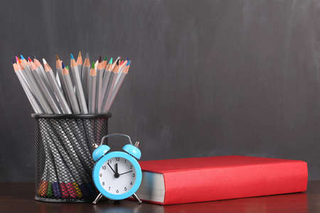 Back to school background with clock, book and pencils over blackboardの写真素材