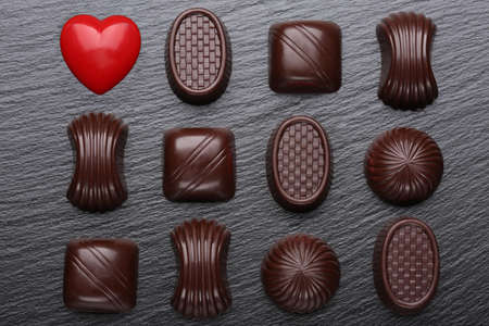Red heart and chocolate candies on black slate stone. Top view. Valentines day greeting card.の写真素材