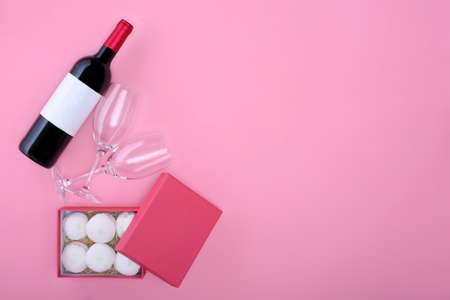 Bottle of red wine with two wineglasses and giftbox over pink backgroundの写真素材