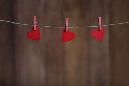 Valentine day greeting card with copy space and hearts pinned to rope on brown wooden backgroundの写真素材