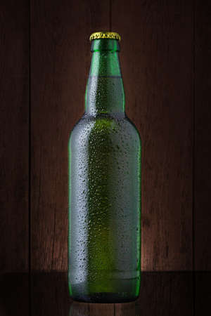 Bottle of beer covered by water drops on gradient brown backgroundの写真素材