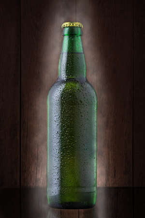 Bottle of beer covered by water drops on gradient brown backgroundの写真素材