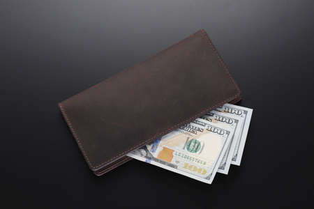 Leather brown wallet with dollars on black table. Top viewの写真素材