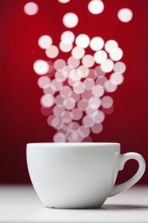 Defocused lights as aroma emanates from white coffee cupの写真素材