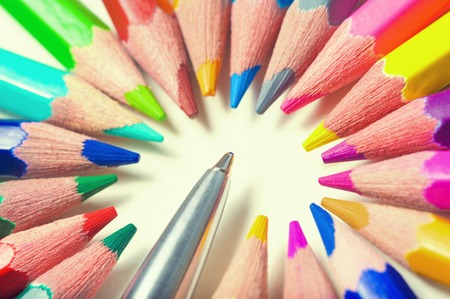 Metal pen among color pencils on yellow light backgroundの写真素材