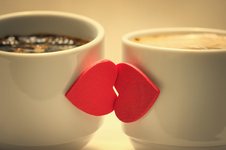 Two coffee cups with red hearts as a kissing lipsの写真素材