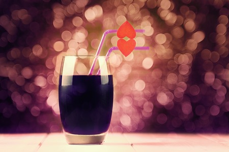 Cherry juice glass with red hearts as a kissing lips on abstract backgroundの写真素材