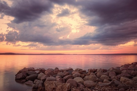 Beautiful landscape, rocks in lake against sunsetの写真素材