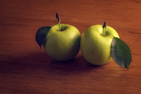 Two fresh green apples with leafs on wooden backgroundの写真素材