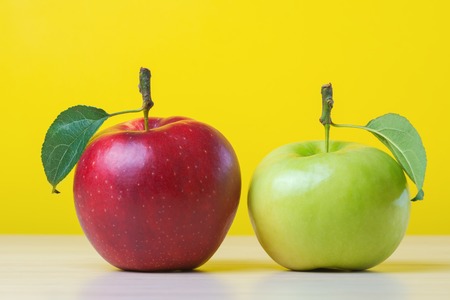 Red and green apples on yellow backgroundの写真素材
