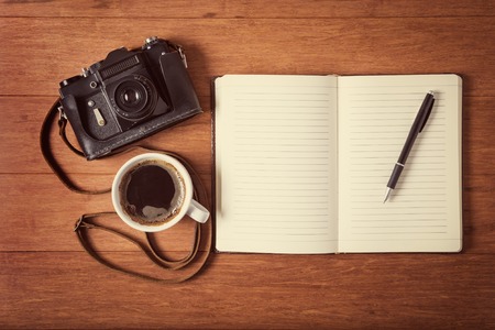 Vintage camera, diary with pan and cup pf coffee on wooden table.  style toned photo.の写真素材