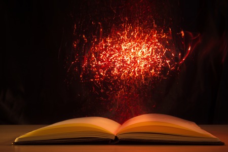 Open book with magic lights on dark background