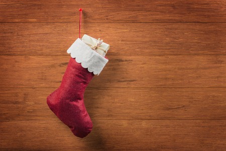 Christmas sock with light yellow gift box on wooden backgroundの写真素材