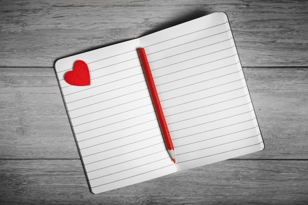 Black and white photo of open notebook with red heart and pencilの写真素材