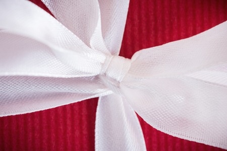 Macro view of decorative white bow on red backgroundの写真素材