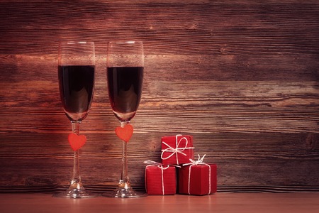 Two wineglasses and gift boxes over vintage wooden backgroundの写真素材