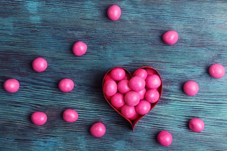 Sweet pink candies in heart shaped box on vintage wooden backgroundの写真素材