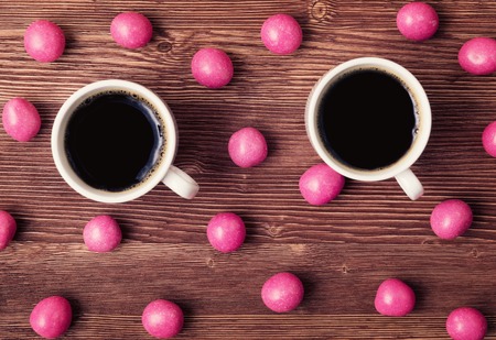 Sweet candies and cups of coffee on vintage wooden backgroundの写真素材