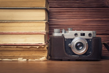 Vintage Camera and Stack of Books Over Wooden  Backgroundの写真素材