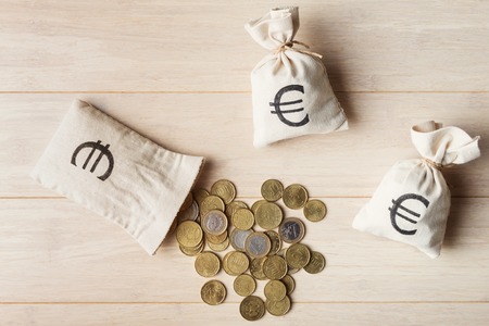 Euro coins with money bags on wooden background, top viewの写真素材
