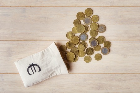 Euro coins with empty money bag over wooden background, top viewの写真素材