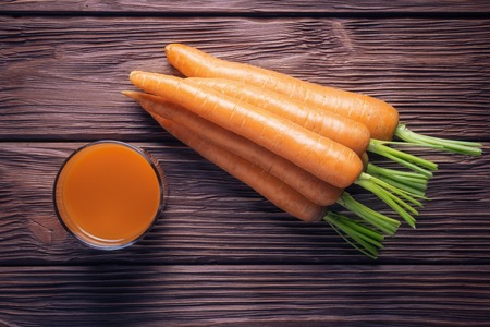 Top view of fresh carrot juice over wooden backgroundの写真素材