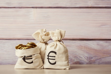 Money bags with euro coins on wooden backgroundの写真素材