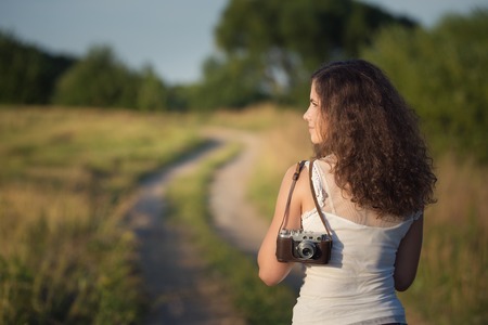 Outdoor portrait of young woman with retro camera