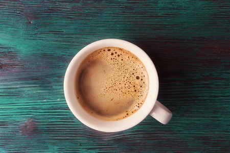 Top view of cup with coffee on vintage wooden background