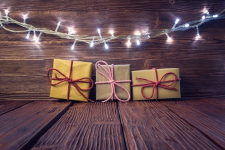 Gift boxes and garland lights over rustic wooden background