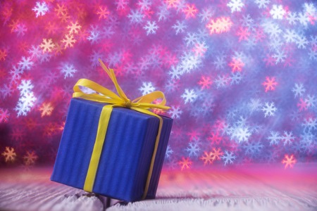 Gift box over defocused lights shaped as snowflakesの写真素材