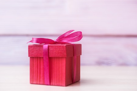 Red gift box over defocused wooden background