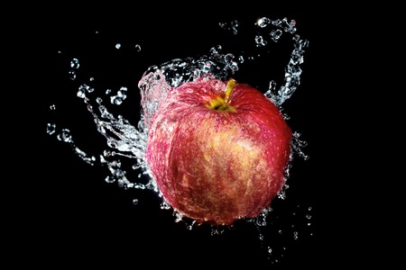 Red apple with water splash over black backgroundの写真素材