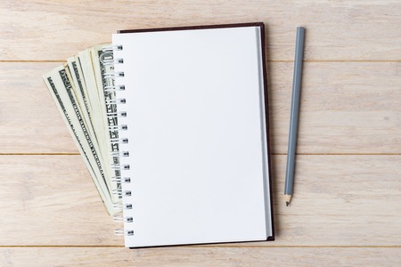 Notebook with USD and pencil on wooden backgroundの写真素材