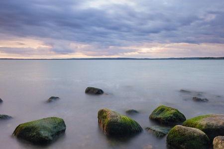 Stones in lake over sunset, long time exposure effect.の写真素材